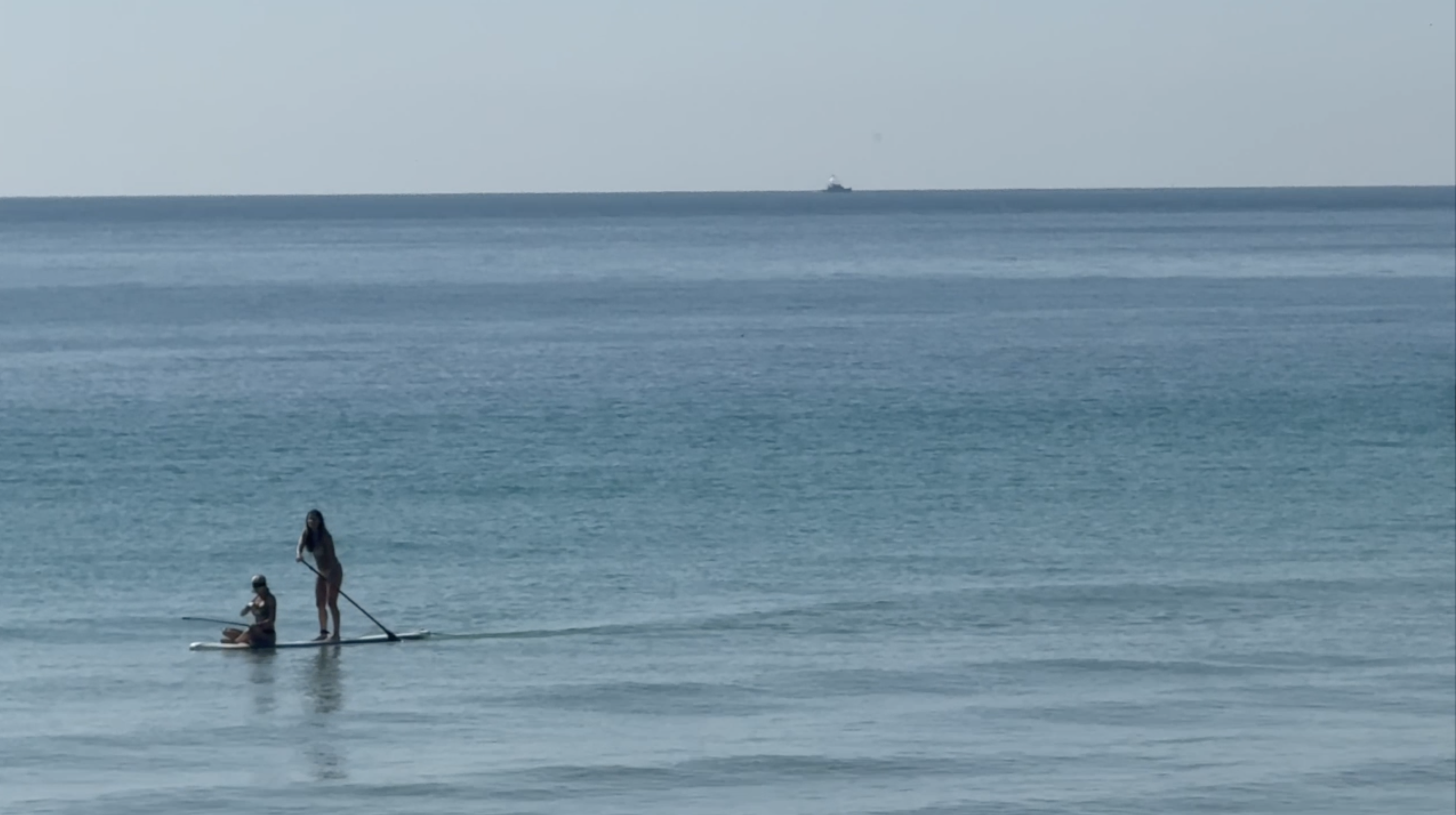 two people paddle boarding on open water
